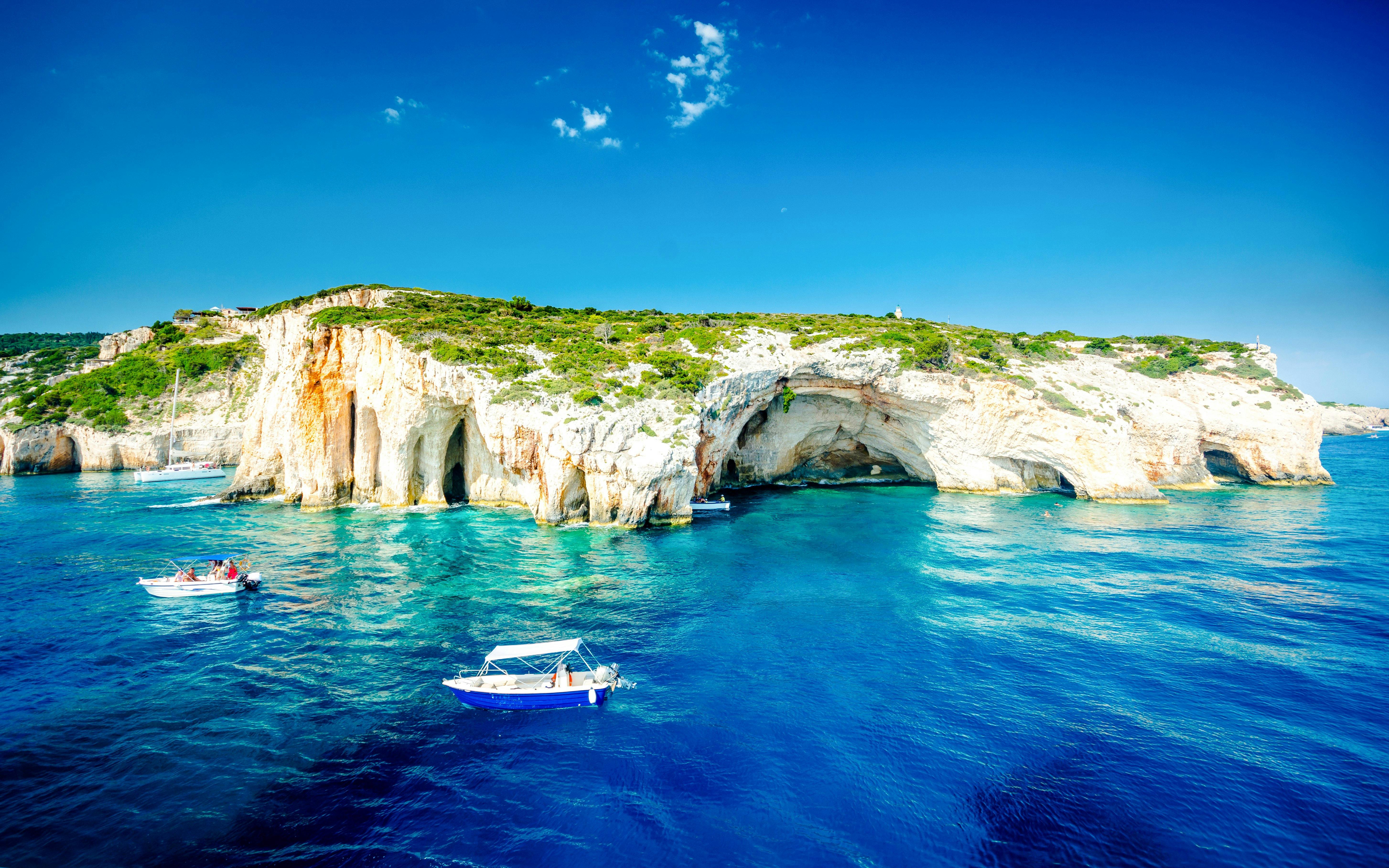 Boats near Blue Caves, Zakynthos, Greece, with clear blue water and rocky cliffs.