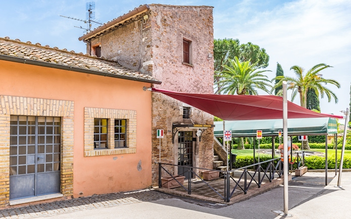 Entrance to the Catacomb of Callixtus on the Appian Way, Italy, with flags and canopy.