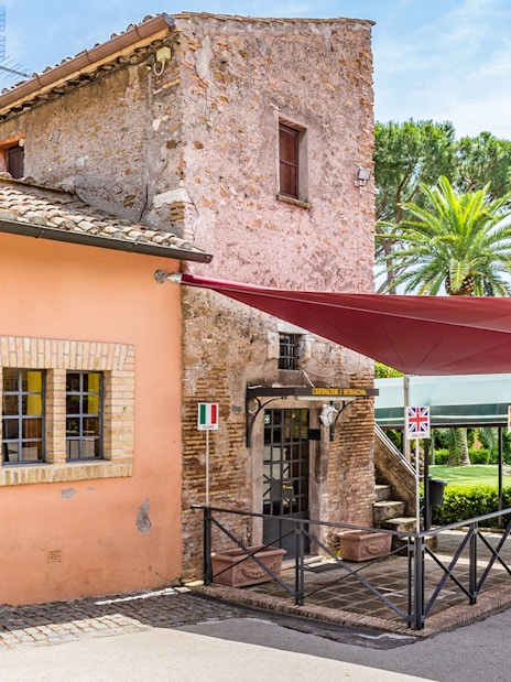 Entrance to the Catacomb of Callixtus on the Appian Way, Italy, with flags and canopy.