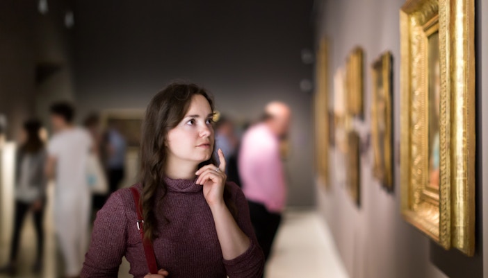 A woman observing paintings in an art museum