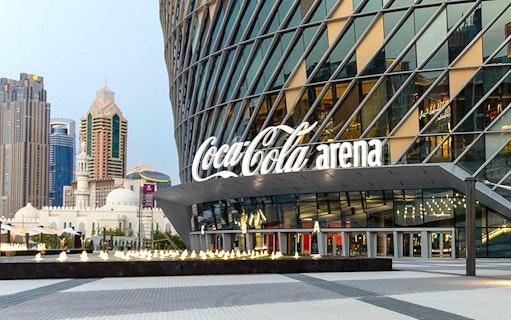 Coca-Cola Arena entrance in Dubai with city skyline in the background.