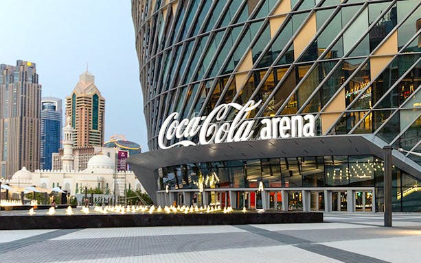 Coca-Cola Arena entrance in Dubai with city skyline in the background.
