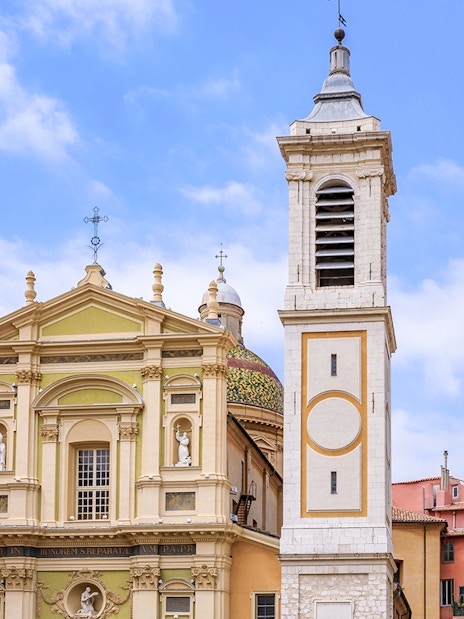 Saint Reparata Cathedral facade and bell tower in Nice, France, surrounded by colorful buildings.
