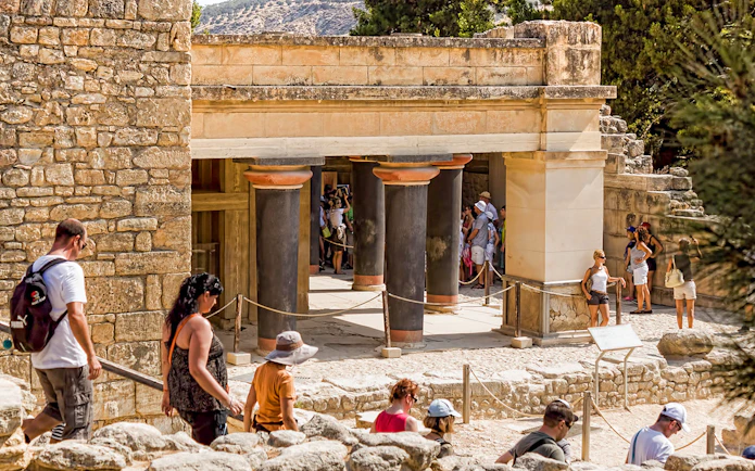 Guided tour group exploring Knossos Palace Archaeological Site in Crete.
