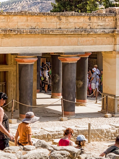 Guided tour group exploring Knossos Palace Archaeological Site in Crete.