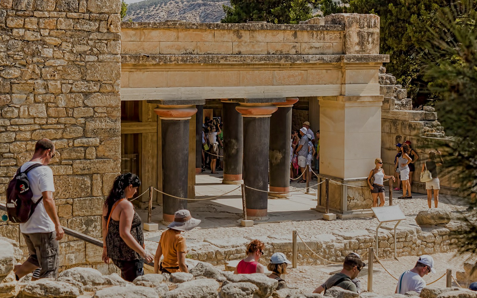 Visitors exploring ancient ruins at Knossos Palace Archaeological Site, Crete, during a guided tour.