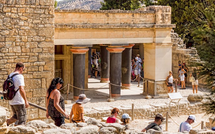 Guided tour group exploring Knossos Palace Archaeological Site in Crete.
