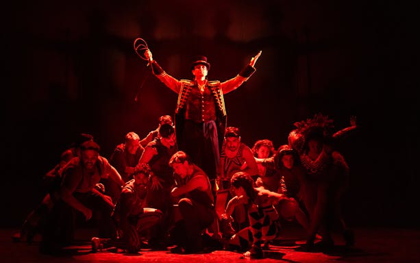 Circus performers in dramatic red lighting during a "Water for Elephants" show.