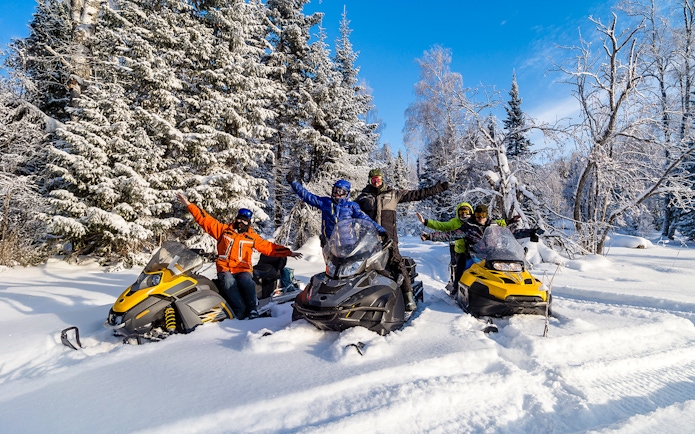 Visitors enjoying snowmobiles in snowy Zakopane forest.