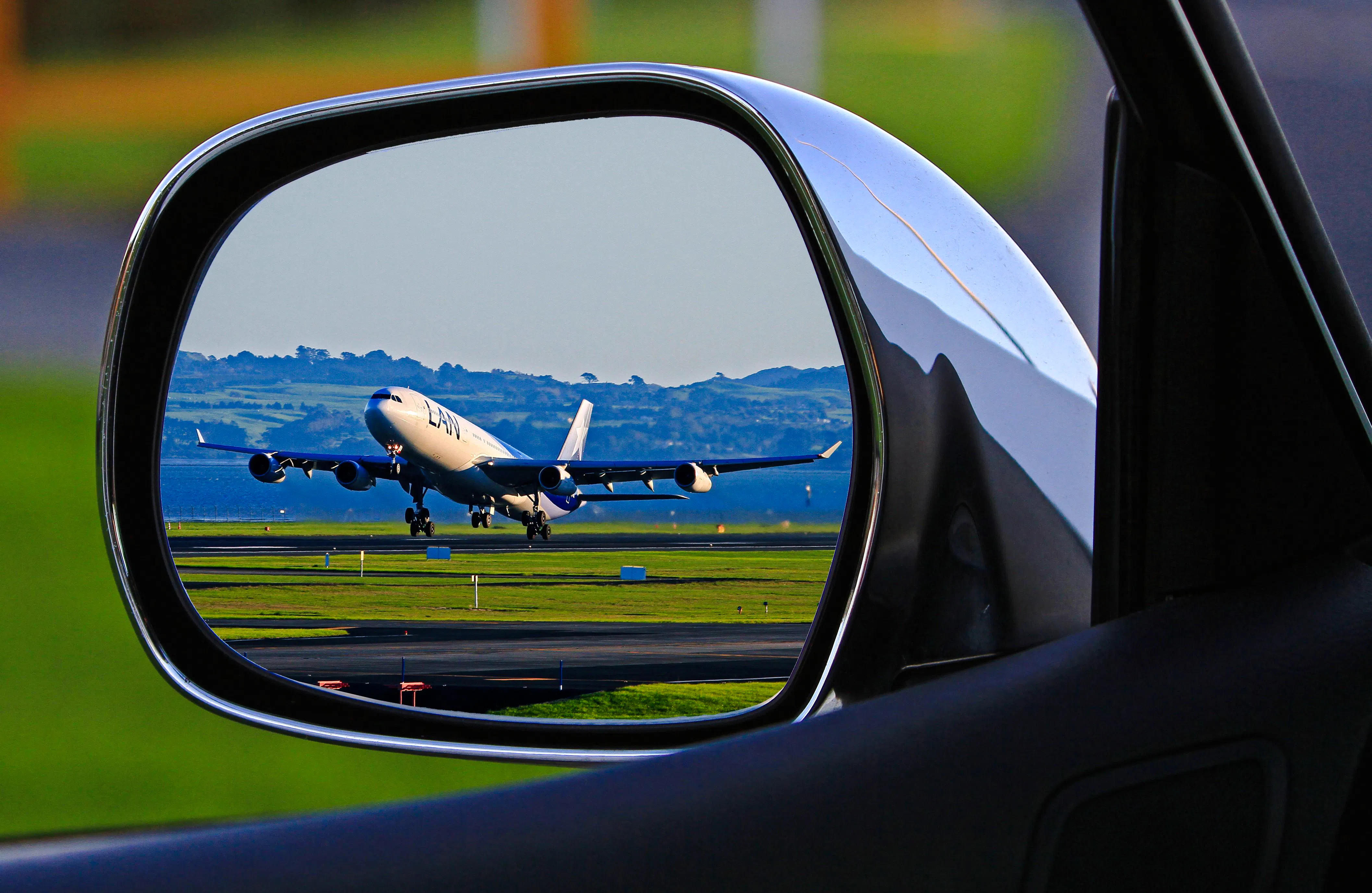 Airplane taking off viewed through car side mirror, representing Zanzibar airport transfers.