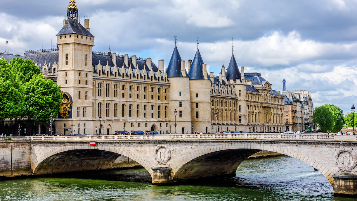 Conciergerie building along the Seine River in Paris with bridge in foreground.
