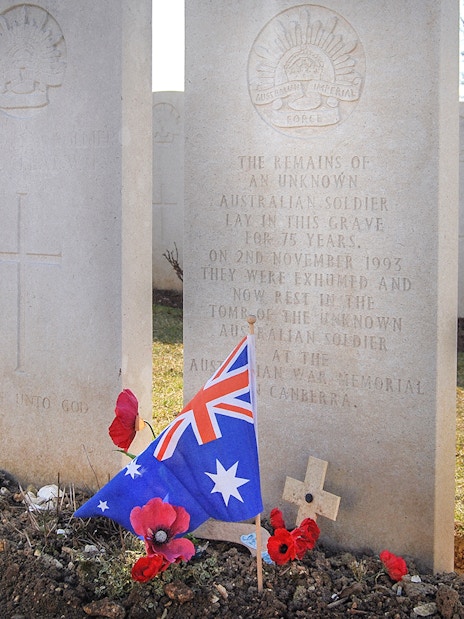 Australian soldier's grave with flag and poppies at Somme battlefield cemetery.