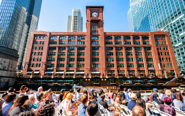 Tourists on a Chicago River cruise view the Britannica Building's clock tower.