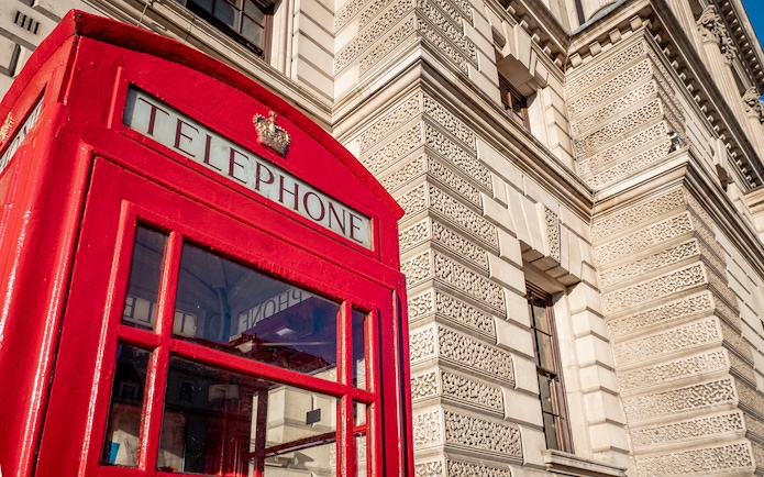 Red telephone box near historic building, London, featured in Harry Potter film locations tour.
