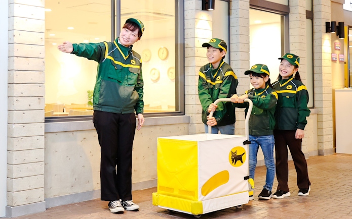Crew guiding children with delivery cart at KidZania Fukuoka.