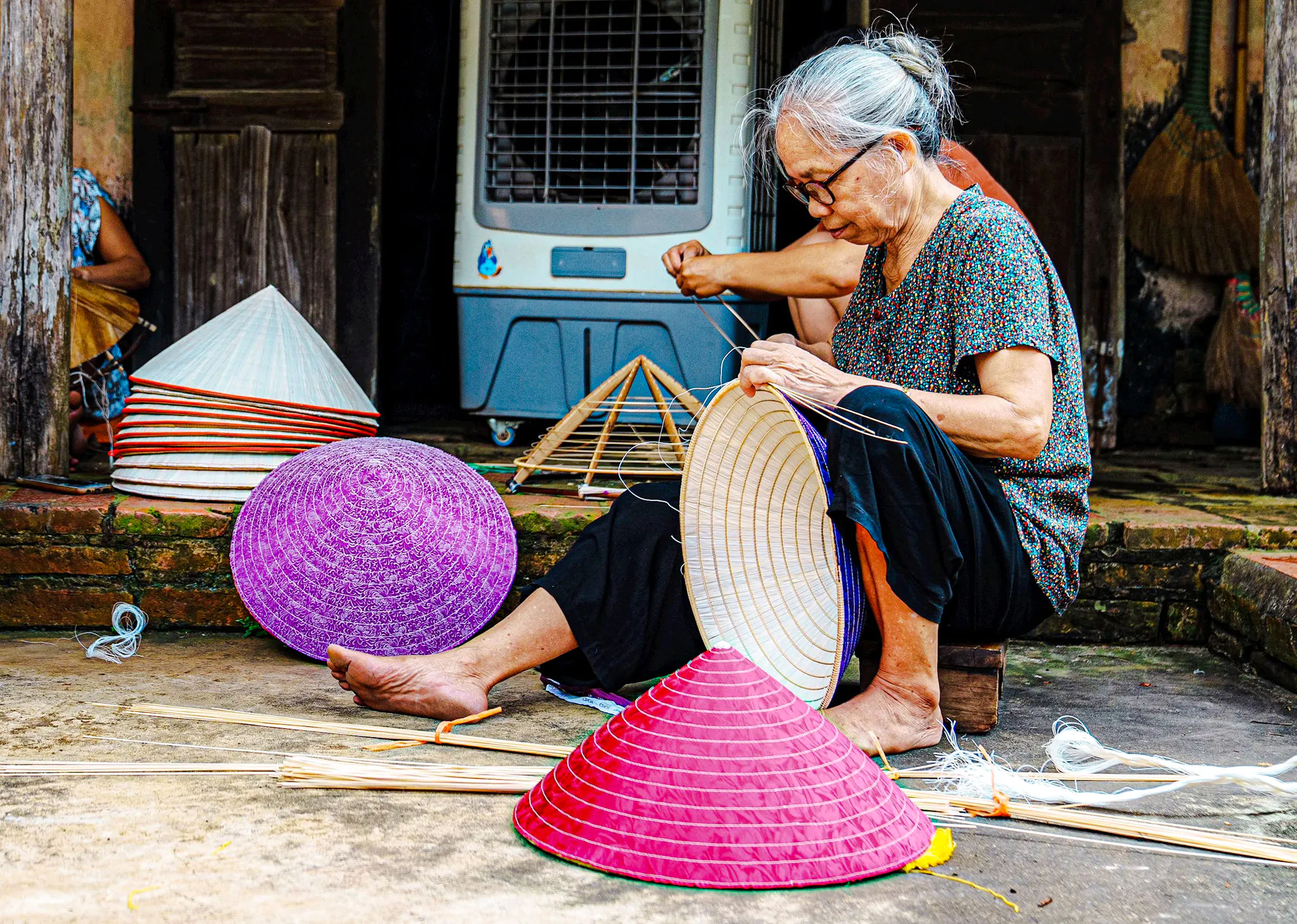 Craftsperson weaving traditional hats in Hanoi's Hat Making Village.
