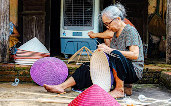 Craftsperson weaving traditional hats in Hanoi's Hat Making Village.