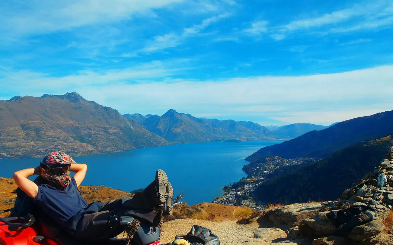 Quad biker relaxing with view of Lake Wakatipu and mountains, Queenstown Quad Bike Tour.