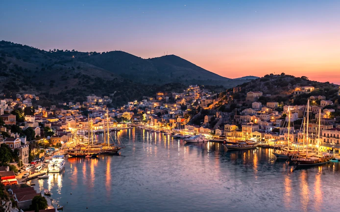 Symi island harbor illuminated at night during Rhodes evening cruise.