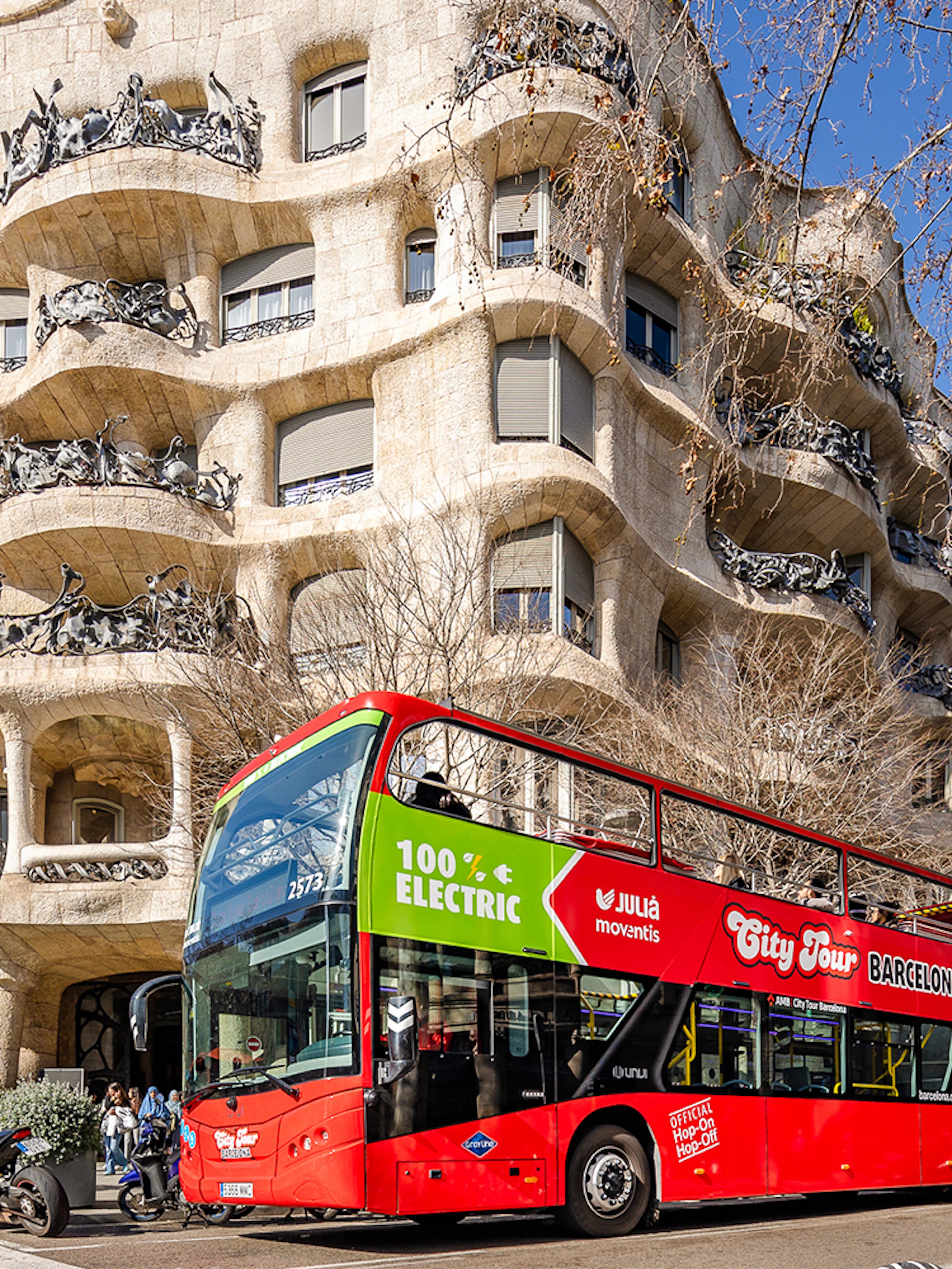 Barcelona hop-on hop-off bus in front of Casa Milà, a Gaudí architectural landmark.