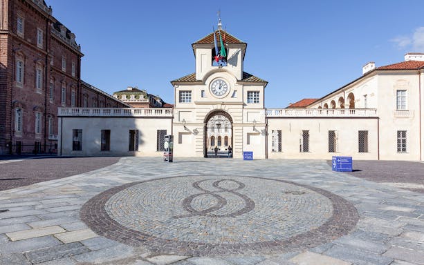 Palace of Venaria entrance with clock tower and cobblestone courtyard in Italy.