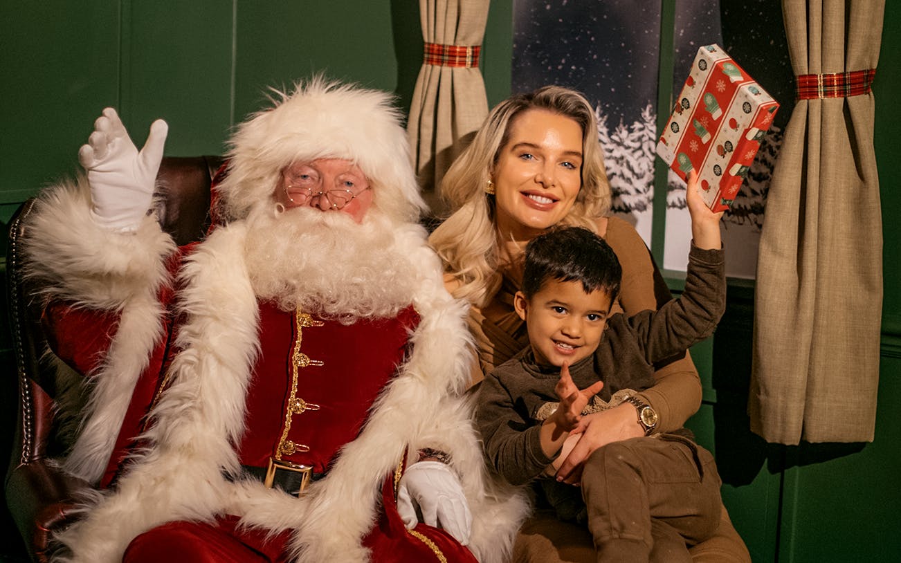 Santa with tourists at Dubai Mall holding a gift.