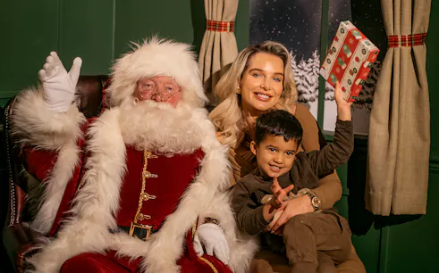 Santa with tourists at Dubai Mall holding a gift.