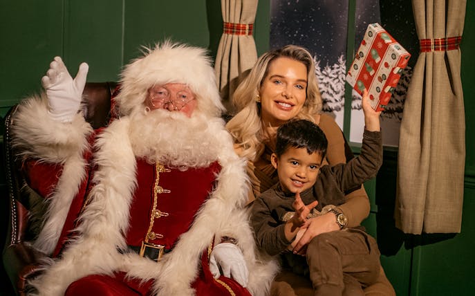 Santa with tourists at Dubai Mall holding a gift.