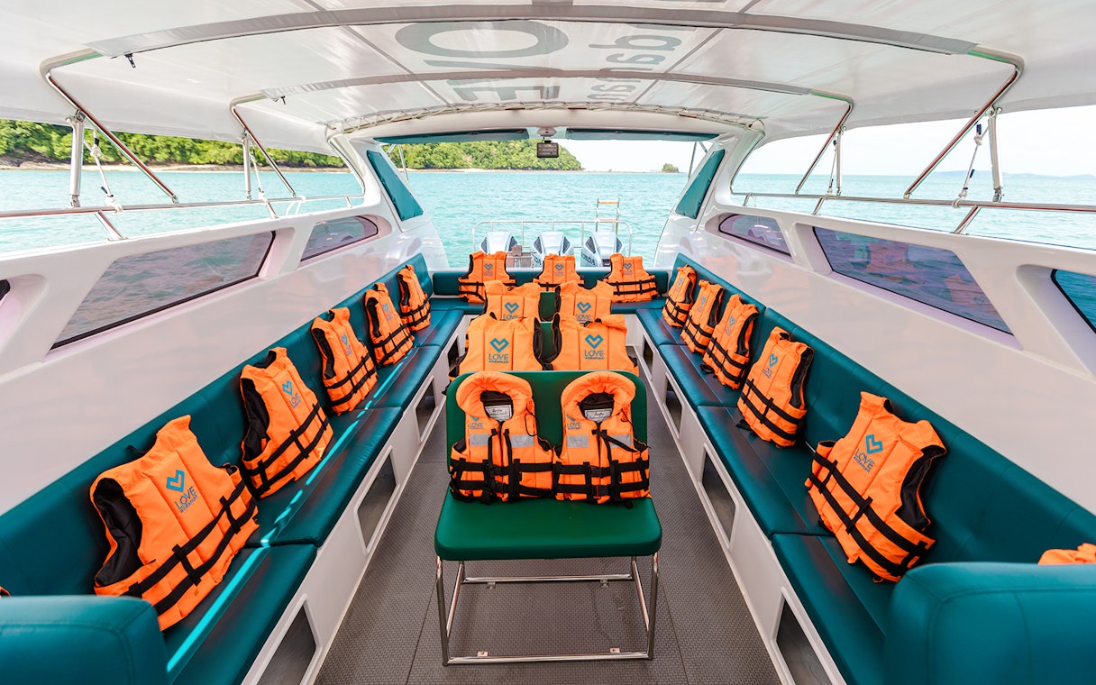Interior of speed boat with rows of seats and orange life jackets.