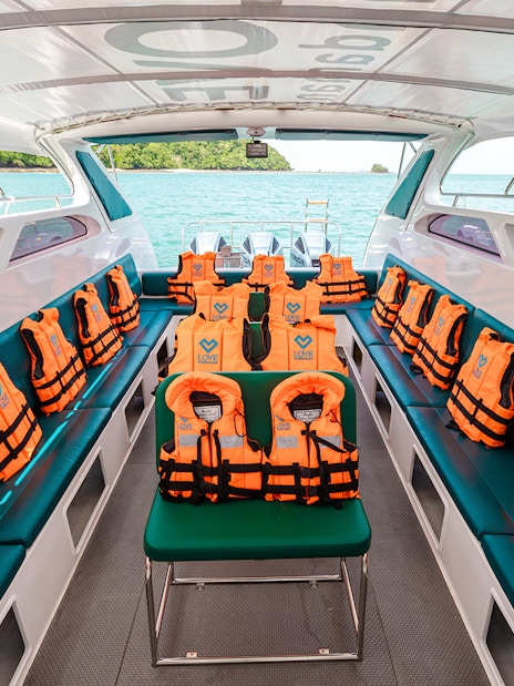 Interior of speed boat with rows of seats and orange life jackets.