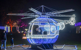 Illuminated helicopter installation at Lumina Park Wonderworld with visitors exploring inside.