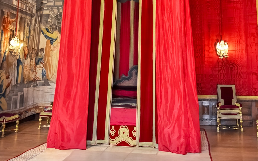 William III’s Apartments at Hampton Court Palace with red drapery and ornate chair.