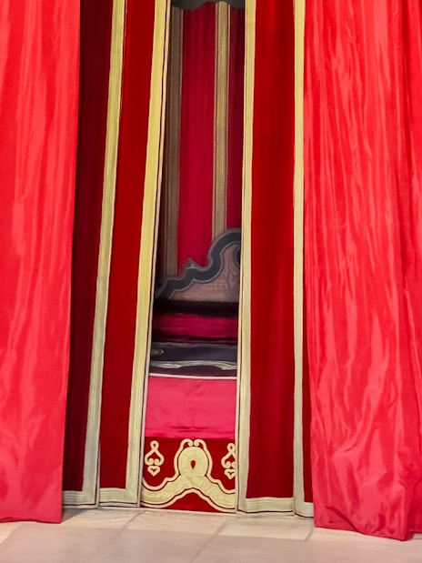 William III’s Apartments at Hampton Court Palace with red drapery and ornate chair.