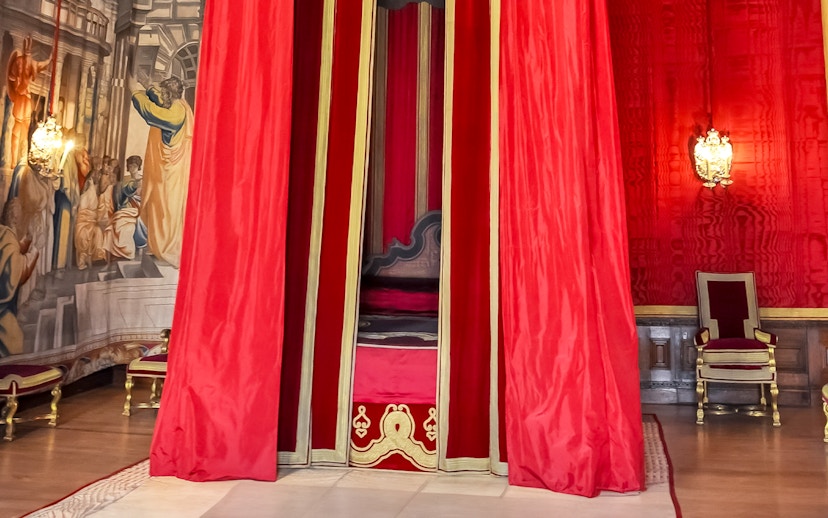 William III’s Apartments at Hampton Court Palace with red drapery and ornate chair.