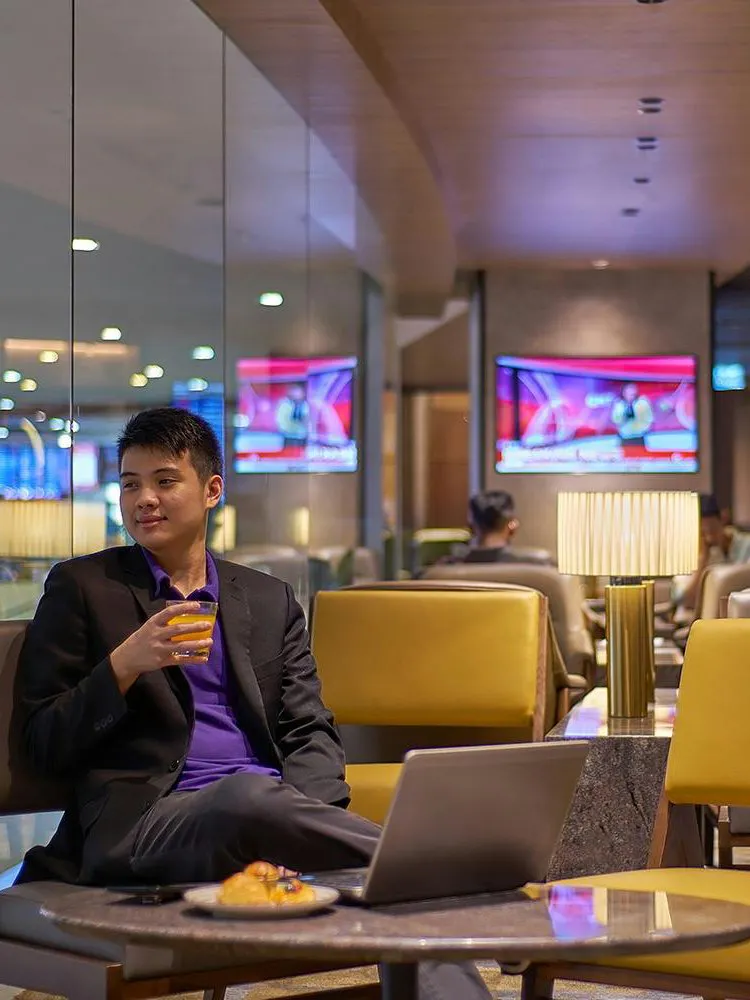 Man relaxing with a drink in Plaza Premium Lounge, Kuala Lumpur International Airport.