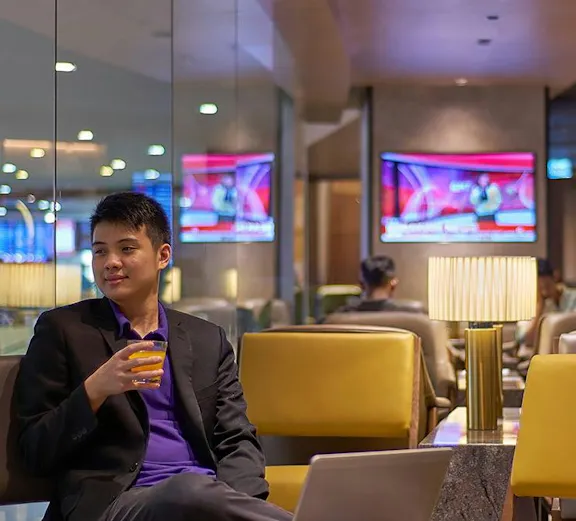 Man relaxing with a drink in Plaza Premium Lounge, Kuala Lumpur International Airport.
