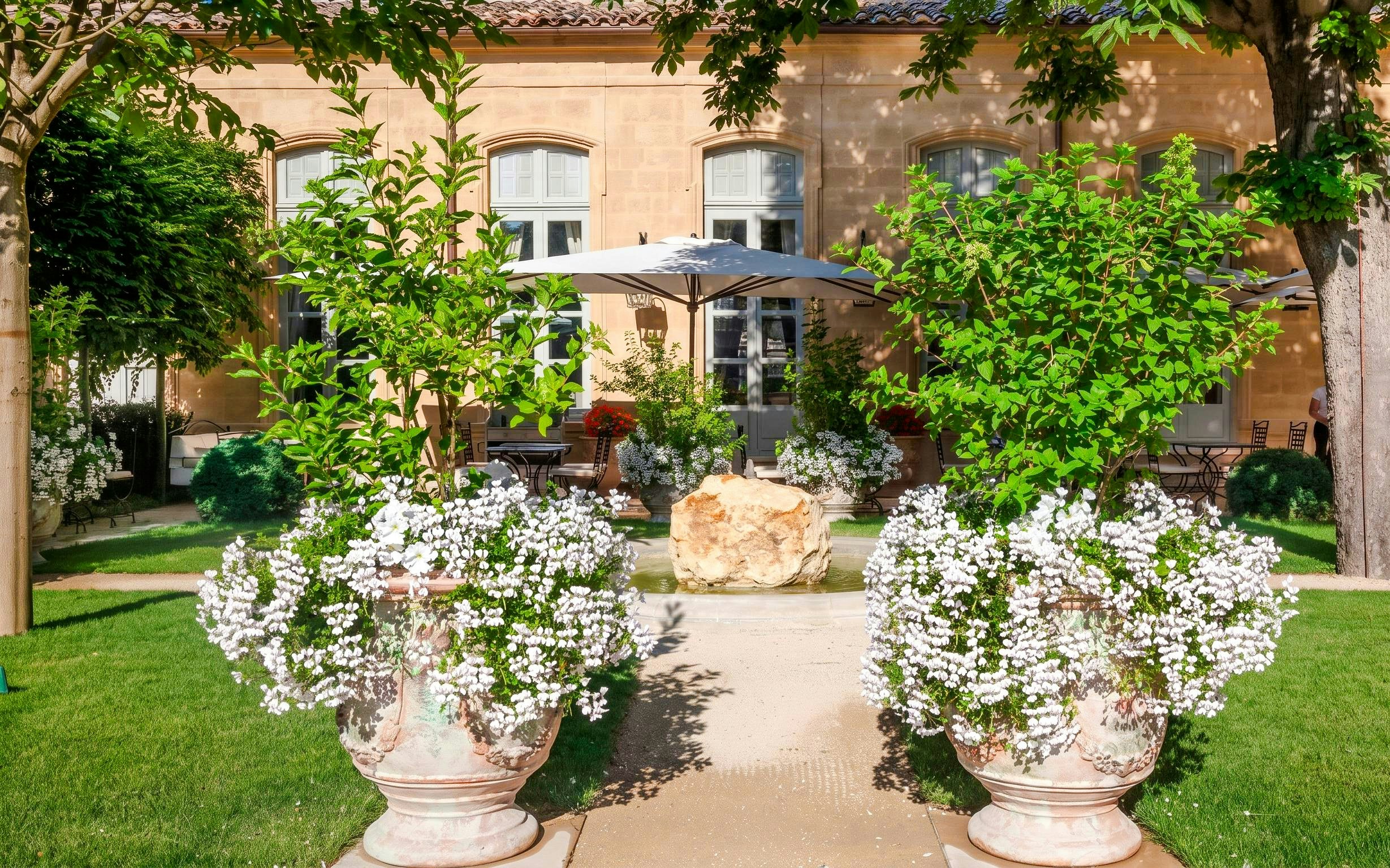 Courtyard garden at Caumont Centre d’Art with potted flowers and outdoor seating.