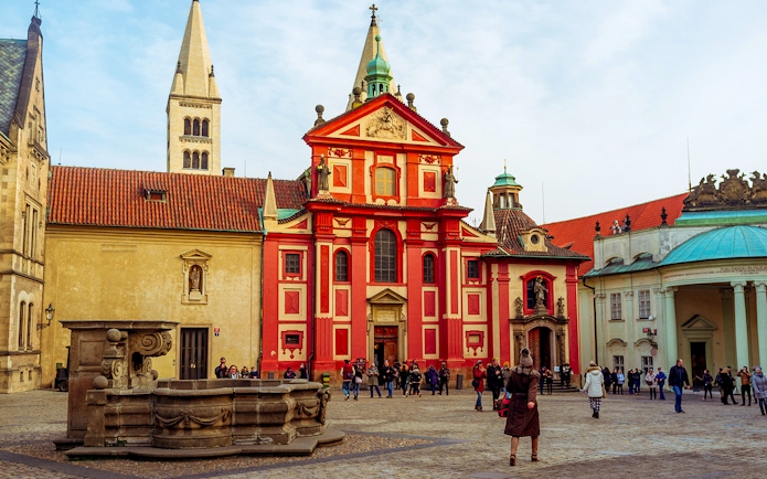 St. George's Basilica at Prague Castle with tourists in the courtyard.