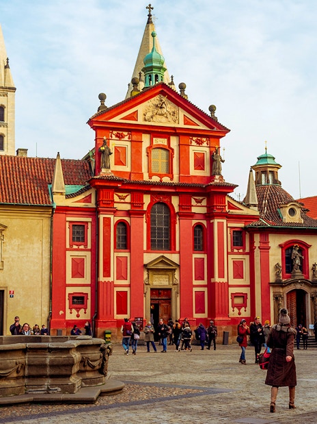 St. George's Basilica at Prague Castle with tourists in the courtyard.