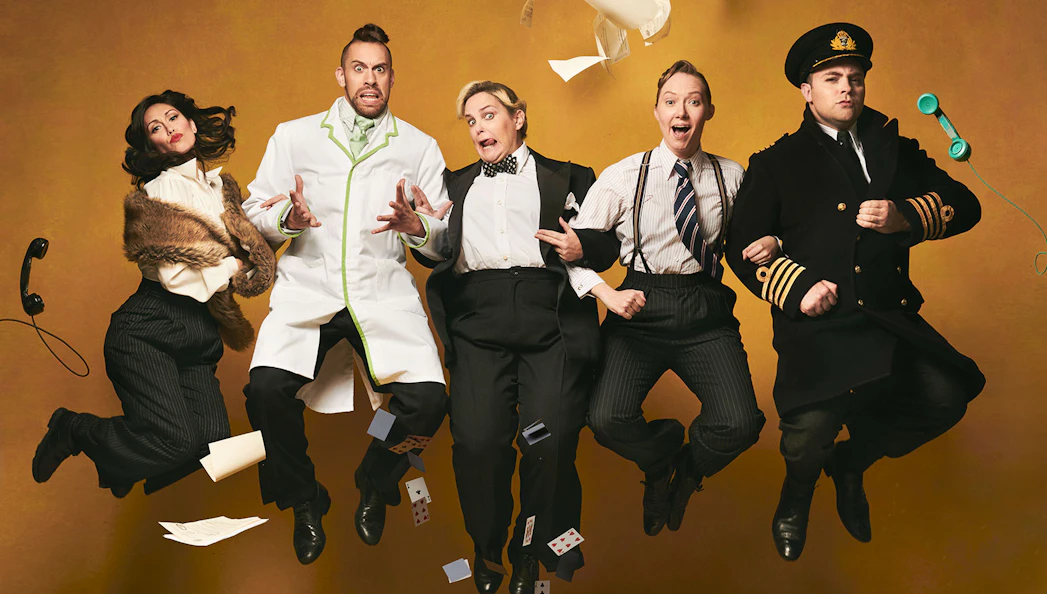 Performers in vintage attire jumping mid-air for "Operation Mincemeat: A New Musical.