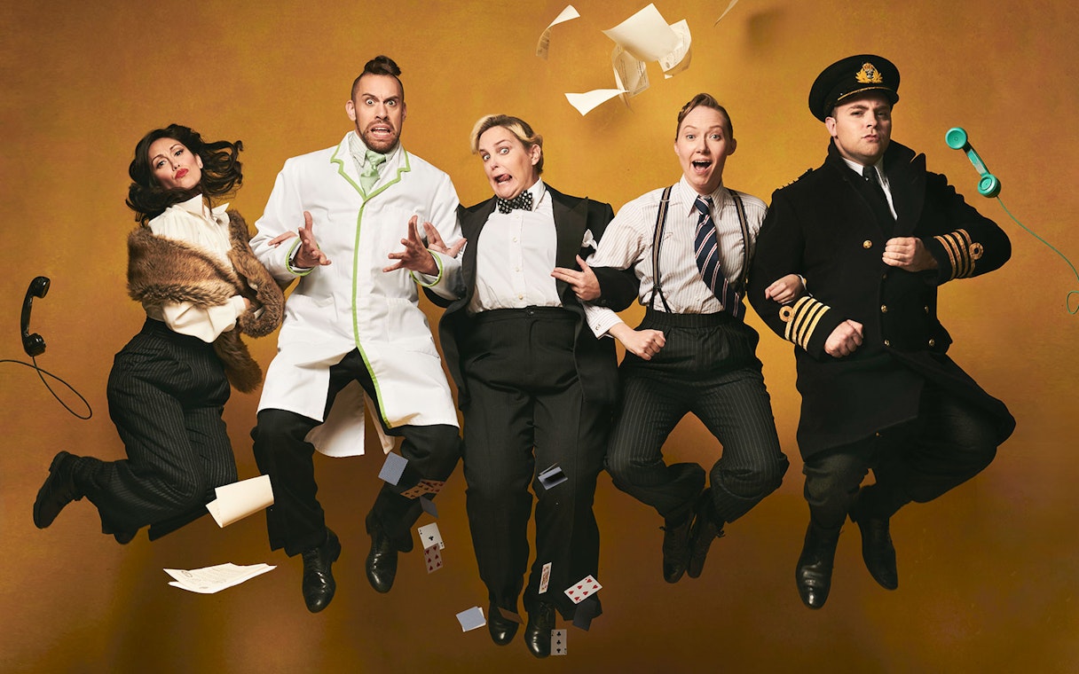 Performers in vintage attire jumping mid-air for "Operation Mincemeat: A New Musical.