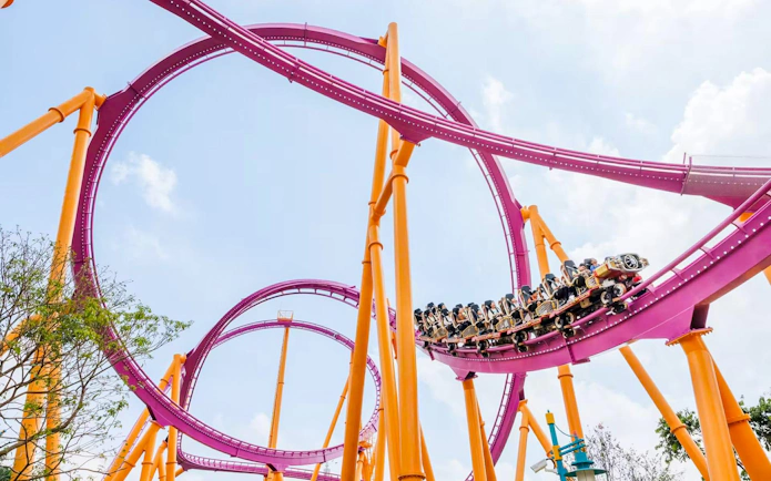 Roller coaster loop at Chimelong Paradise, Guangzhou, with riders on a vibrant pink track.