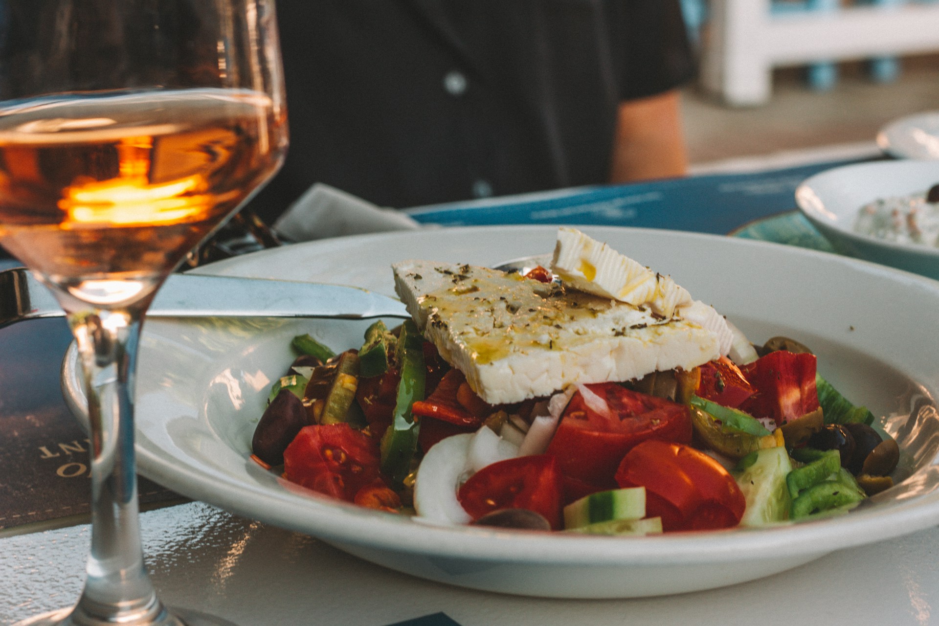 sliced tomato and cucumber on white ceramic plate. A classic Greek salad.