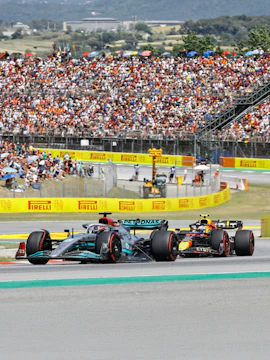 Formula 1 cars racing at Circuit de Barcelona-Catalunya with a large crowd in the stands.