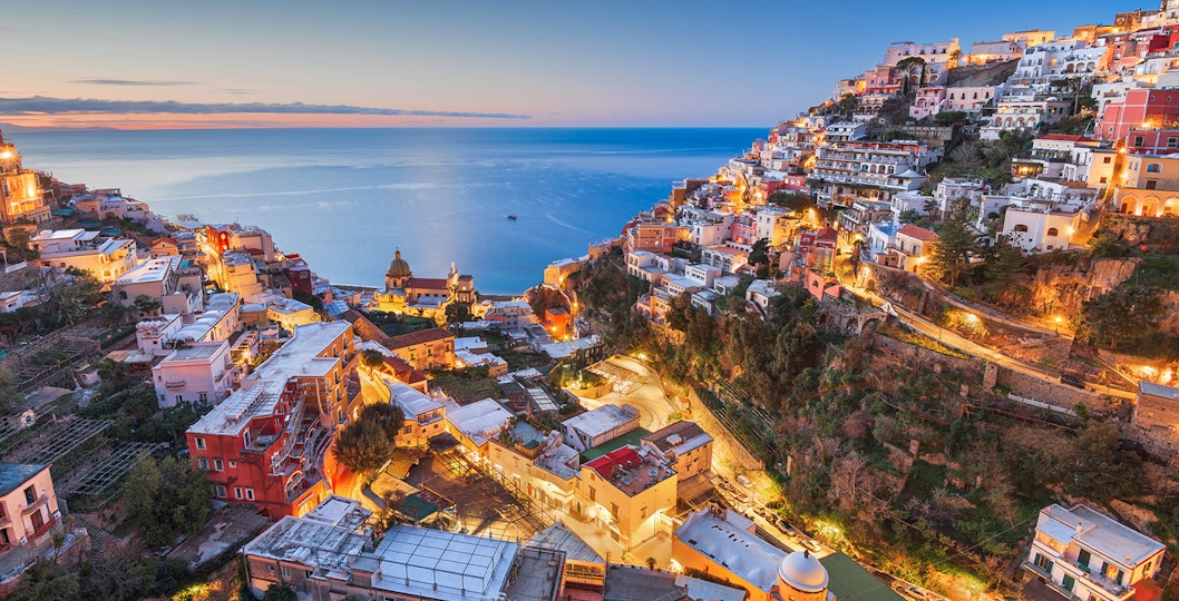 Sorrento coastline at sunset with illuminated buildings and sea view.