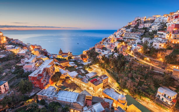 Sorrento coastline at sunset with illuminated buildings and sea view.