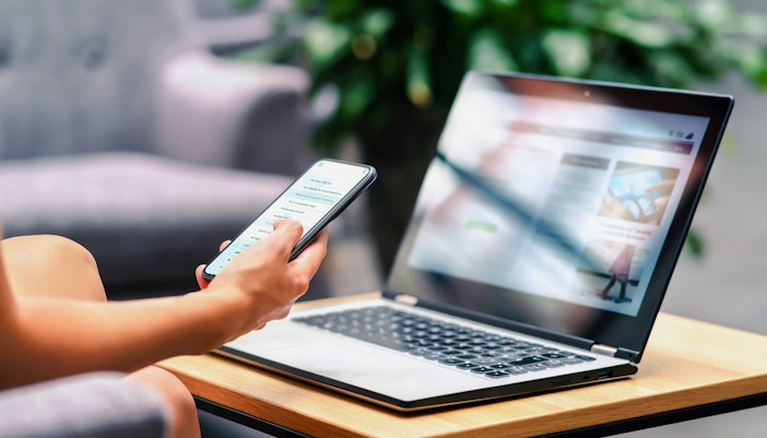 Person using smartphone and laptop in a lounge with wifi access.