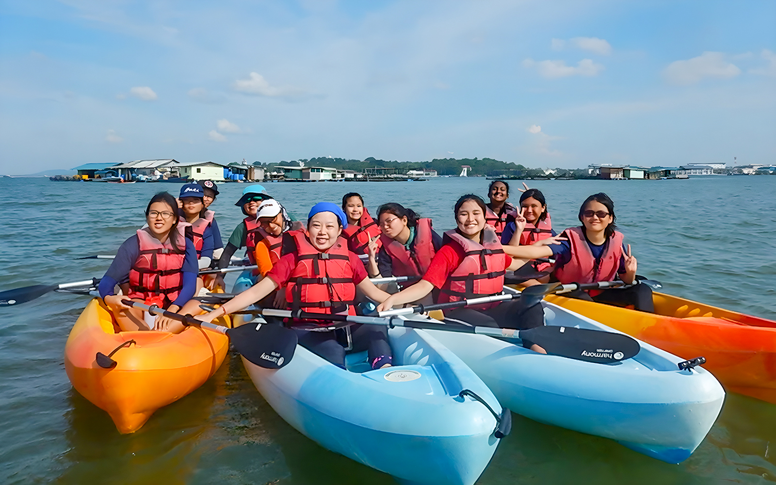 Kayakers in life vests paddling near floating houses at Pulau Ubin, Singapore.