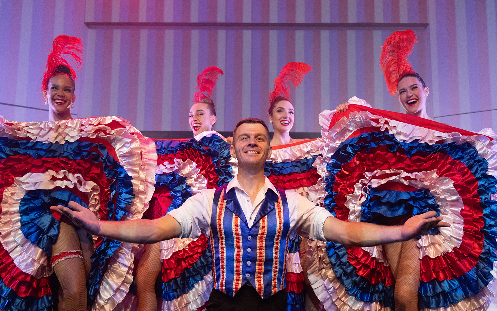 Cabaret performers in colorful costumes on a cruise with 3-course dinner.