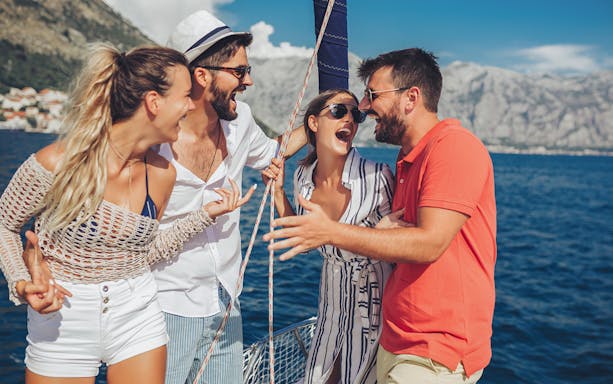 Group enjoying a boat tour from Fertilia to Bay of Alghero with mountains in the background.